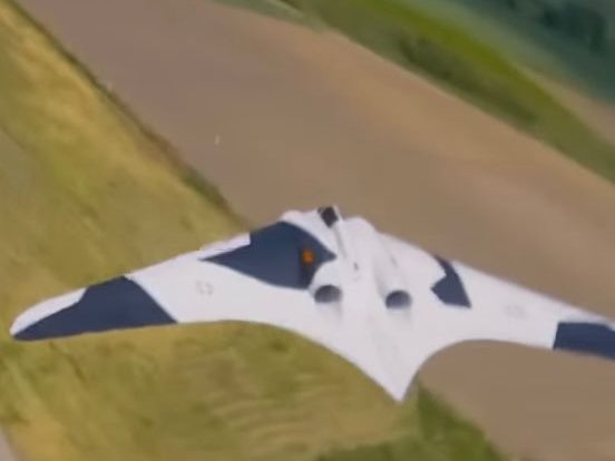 Weiß-schwarze Nurflügel-Drohne im Flug über einem Feld